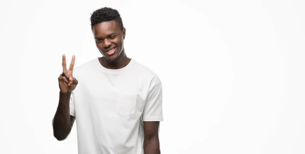 若いアフリカ系アメリカ人を示すと指で上向きの白い シャツを身に着けている数は自信を持って 幸せな笑みを浮かべている間 — ストック写真