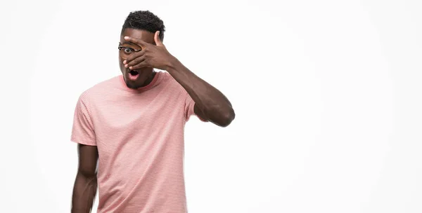 Joven Hombre Afroamericano Vistiendo Camiseta Rosa Asomándose Shock Cubriendo Cara — Foto de Stock