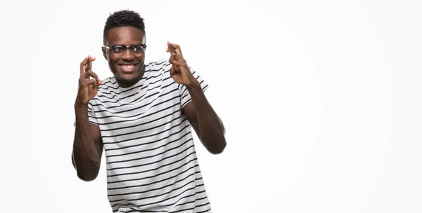Jovem Afro Americano Vestindo Óculos Camiseta Marinha Sorrindo Cruzando Dedos — Fotografia de Stock