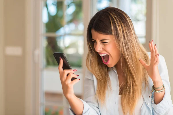 Frustrated woman using smartphone, shouting. Bad emotion at home