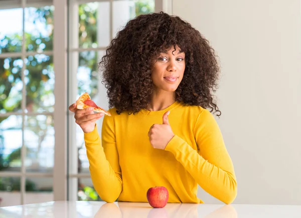 非洲裔美国妇女选择在苹果和比萨切片高兴与大微笑做 拇指与手指 优秀的标志 — 图库照片