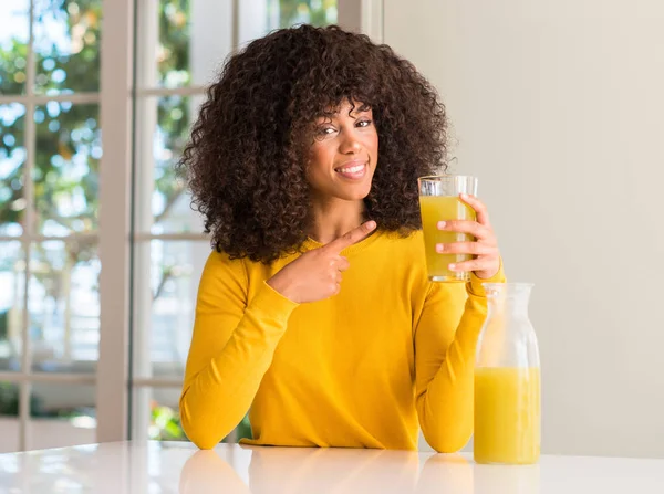 非洲裔美国妇女饮用健康果汁在家中非常高兴地指着手和手指 — 图库照片