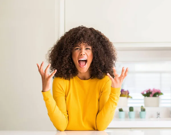 穿着黄色毛衣的非洲裔美国妇女在厨房疯狂和疯狂的呼喊和挑衅的表达和手臂举起 挫折概念 — 图库照片