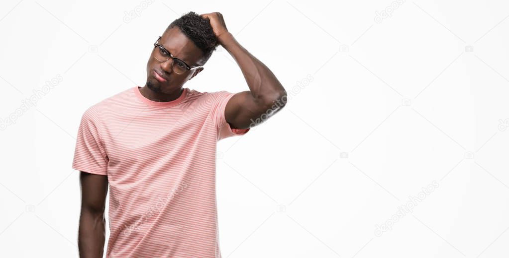 Young african american man wearing pink t-shirt confuse and wonder about question. Uncertain with doubt, thinking with hand on head. Pensive concept.