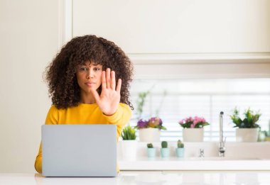 Afrikalı-Amerikalı kadın açık eliyle dur işareti ile ciddi ve kendine güvenen ifade, savunma hareketi yapmaya mutfağa bilgisayar dizüstü kullanarak