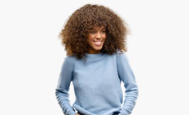 Uzak tarafına yüzünde, doğal ifade gülümseme ile seyir süveter giyen Afrikalı-Amerikalı kadın. Kendine güvenen gülüyor.