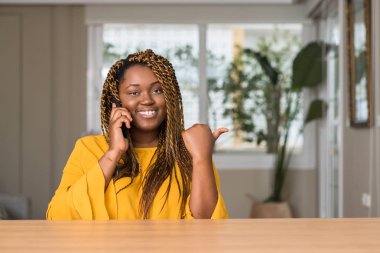 Afrikalı-Amerikalı kadın el ve parmak ile yukarı dönük mutlu yüz gülümseyen ile smartphone kullanarak