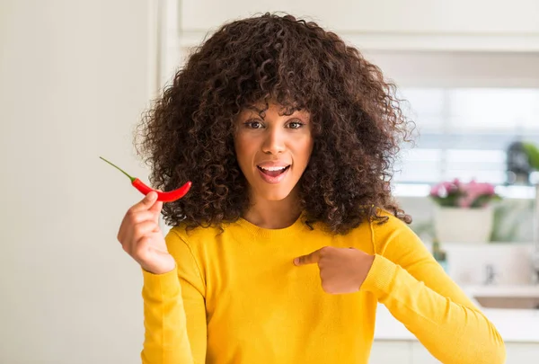 非洲裔美国妇女吃红辣椒与惊喜脸指向自己的手指 — 图库照片
