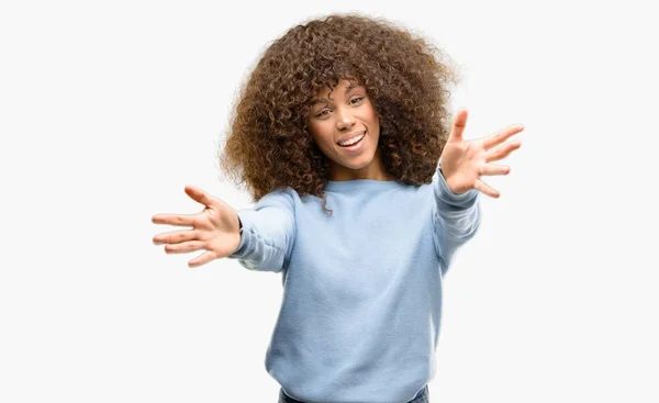 アフリカ系アメリカ人の女性はハグするため両手を広げて笑みを浮かべてカメラを見ているセーターを着ています 晴れやかな表情の受け入れ幸せ — ストック写真