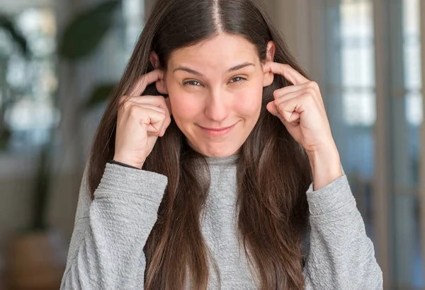 若い美しい女性を自宅は 騒々しい音楽のノイズの腹が立つ式の指で耳をカバーします 聴覚障害者の概念 — ストック写真