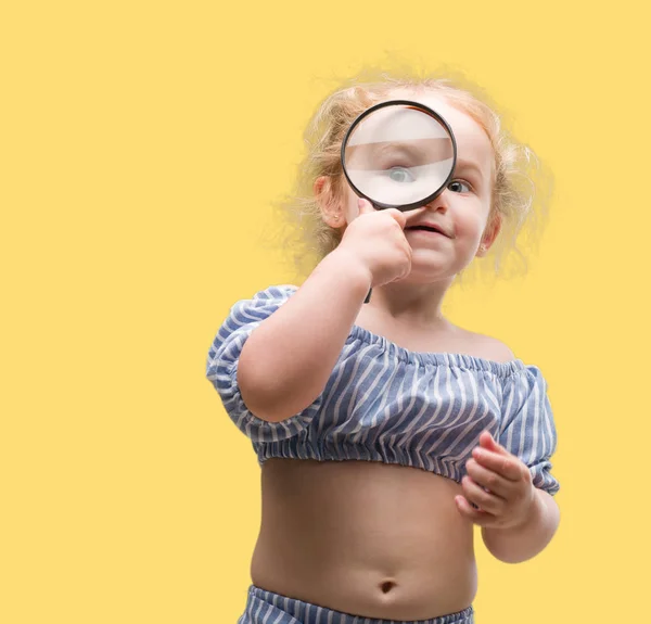 虫眼鏡で何かを探している美しい金髪の幼児 — ストック写真