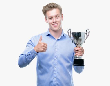 Genç yakışıklı sarışın adam ok işareti, başparmak ile parmak, mükemmel işareti yapıyor kocaman bir gülümseme ile bir kupa mutlu holding