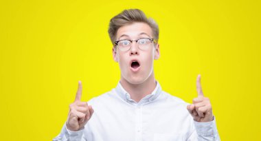 Genç yakışıklı sarışın adam hayret ve yukarıya bakıp parmakları ile işaret şaşırttı ve silah kaldırdı.