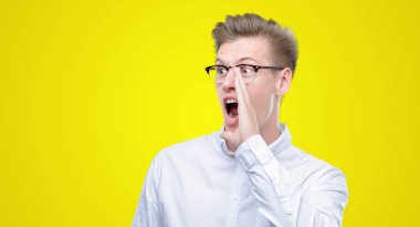 Bağırarak ve ağzı üzerinde el ile yan için çığlık genç yakışıklı sarışın adam. İletişim kavramı.