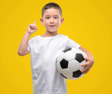 Futbol topu bir fikir ya da soru işaret parmağı gülen yüz, bir numara ile sürpriz ile oynayan koyu saçlı küçük çocuk