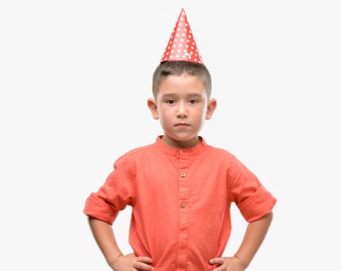 Koyu saçlı küçük çocuk Doğum günü şapkası kendine güvenen bir ifade ile acımak yüz ciddi düşünme