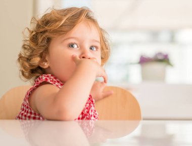 Mavi gözlü kapsayan ağız evde gülümseyen güzel sarışın çocuğun.