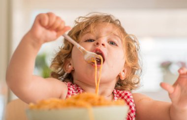 Güzel sarışın çocuk spagetti çatalı ile evde yemek
