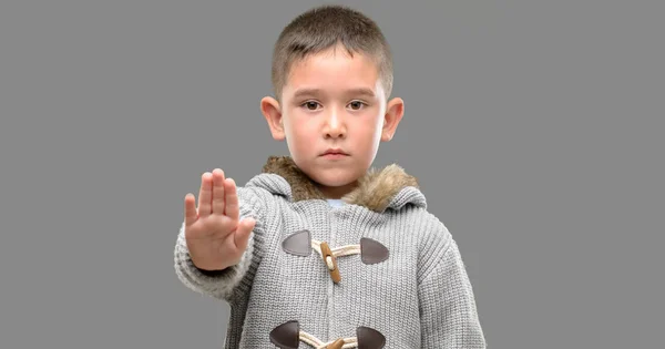 黑发小孩穿着一件外衣张开手做停止标志以严肃和自信的表达 防御手势 — 图库照片