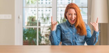 Kızıl saçlı kadın deli ifade rock simge elle yapıyor ile ev bağırarak. Müzik yıldızı. Ağır kavramı.