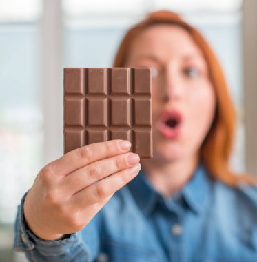 Çikolata bar evde bir sürpriz yüz, korkuyor ve heyecanlı korku ifadesi ile şok korkmuş tutan Kızıl saçlı kadın