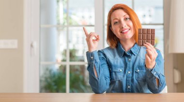 Çikolata bar evde el ve parmak ile tarafına işaret çok mutlu tutan Kızıl saçlı kadın