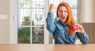 Ev rahatsız ve hayal kırıklığı ile öfke, çılgın ve yükseltilmiş eliyle diye bağıran öfke kavramı bağırarak, kırmızı elma tutan Kızıl saçlı kadın