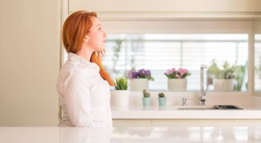 Kızıl saçlı kadına mutfak tarafına, seyir dinlenmek doğal yüz emin gülümseme ile pozuyla profil.