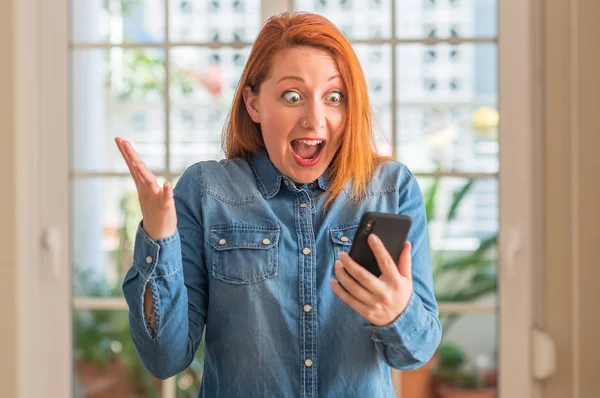 Ruda Kobieta Przy Użyciu Smartfona Domu Bardzo Szczęśliwy Podekscytowany Zwycięzca — Zdjęcie stockowe