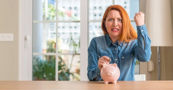 Rödhårig Kvinna Sparar Pengar Piggy Bank Hemma Irriterad Och Frustrerad — Stockfoto