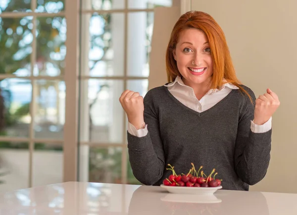 Redhead Woman Eating Cherries Home Screaming Proud Celebrating Victory Success — Stock Photo, Image