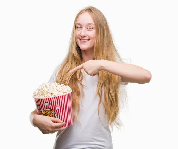 ポップコーンの手と指で指している非常に幸せを食べるブロンド十代の若者女性 — ストック写真