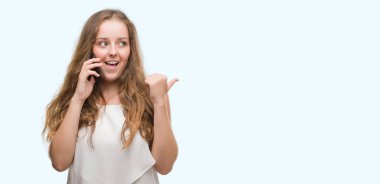 Genç Sarışın kadın işaret ve başparmak kadar mutlu yüz gülümseyen tarafı ile gösterilen smartphone kullanarak