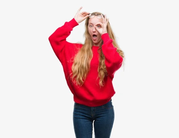 のジェスチャーを行う赤いセーターを着ている金髪の 代女性は驚いた顔 指を通して見る目でショックを受けました 疑うような式 — ストック写真