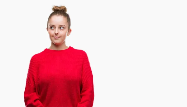 お団子と笑って見ている側と見つめて離れて思考赤いセーターを身に着けている若いブロンドの女性 — ストック写真