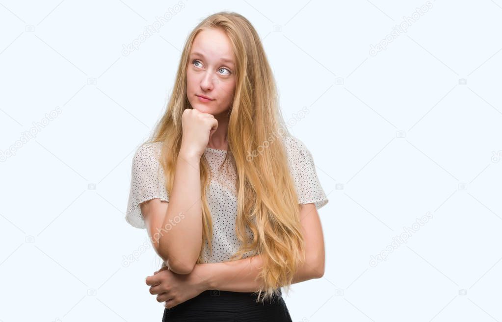 Blonde teenager woman wearing moles shirt with hand on chin thinking about question, pensive expression. Smiling with thoughtful face. Doubt concept.