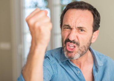 Yakışıklı orta yaş erkek rahatsız ve öfkeyle, çılgın ve yükseltilmiş eliyle diye bağıran öfke kavramı bağırarak sinirli