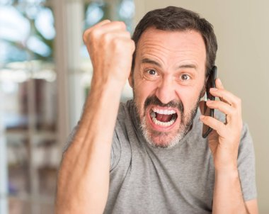 Akıllı telefon kullanan orta yaş adam rahatsız ve boşa çıkarmak ile öfke, çılgın da yükseltilmiş el ile bağırmaya kavramı öfke