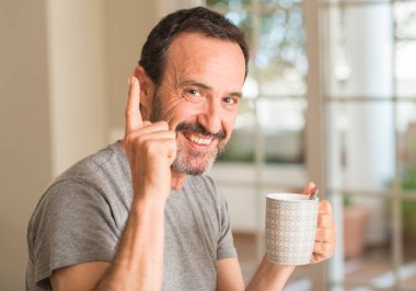 Gülen yüz, bir numara ile bir fikir ya da soru işaret parmağı ile orta yaş erkek bir fincan kahve içme şaşırttı