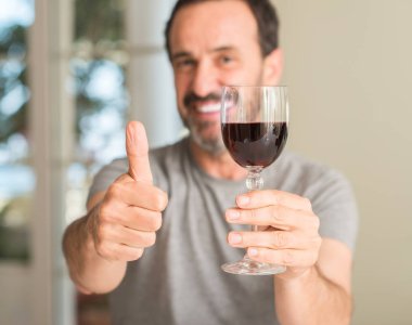 Ok işareti, başparmak ile parmak, mükemmel işareti yapıyor kocaman bir gülümseme ile bir kadeh şarap mutlu içme orta yaş erkek