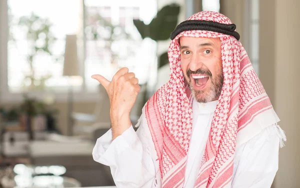 Middle age arabian man at home pointing with hand and finger up with happy face smiling
