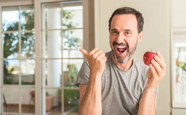 Homem Meia Idade Comendo Maçã Vermelha Saudável Apontando Com Mão — Fotografia de Stock