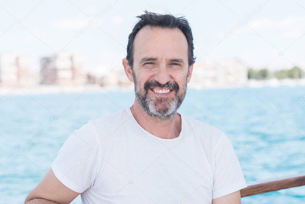 Handsome senior man traveling on sailboat and smiling happy and confident