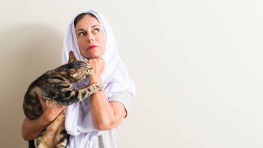 Soru çok karışık fikir hakkında düşünme bir kedi ciddi bir yüz tutan beyaz hijab giyen Arap kadın