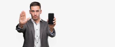 Açık eliyle dur işareti ile ciddi ve kendine güvenen ifade, savunma jest yapıyor Smartphone kullanarak yakışıklı genç