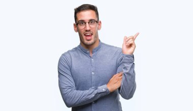 Kameraya bakarak yan el ve parmak ile işaret yüzünde, kocaman bir gülümseme ile gözlüklü zarif yakışıklı genç.