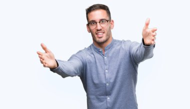 Yakışıklı genç zarif gözlük sarılmak için kollarını açarak gülümseyerek kameraya bakarak adam. Neşeli ifade kucaklayan mutluluk.