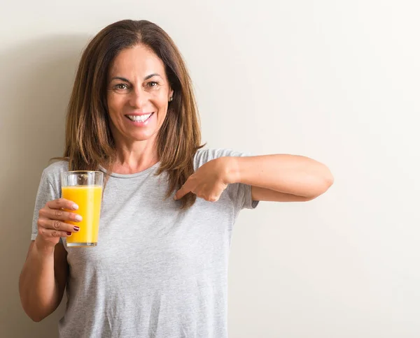 Medelålders Kvinna Dricker Apelsinjuice Ett Glas Med Överraskning Ansikte Pekande — Stockfoto