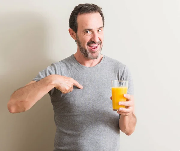 Senior Man Drinking Orange Juice Glass Surprise Face Pointing Finger — Stock Photo, Image
