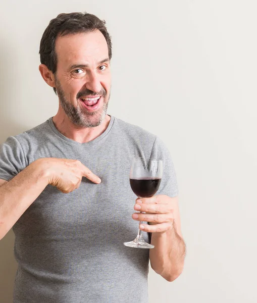 自分自身に驚き顔ポインティング指でガラスの赤ワインを飲む年配の男性 — ストック写真